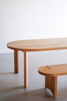 a wooden table and bench sitting on top of a cement floor in front of a white wall