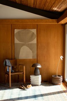 a room with wood paneling and a painting on the wall next to a chair