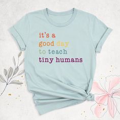 Teacher Shirt, It's A Good Day To Teach Tiny Humans Tshirt, Back to School Teacher Life Shirts, Teacher Gift Tee, Preschool Teacher Outfits  Start your day with positivity and purpose in our "It's A Good Day To Teach Tiny Humans" Tshirt! This charming Teacher Shirt is perfect for educators who bring joy and creativity to their classrooms. Whether you're gearing up for the new school year or looking for the ideal Teacher Gift Tee, this shirt is designed to inspire. Ideal for Back to School Teache Cotton School T-shirt With Slogan, Funny Text Print T-shirt For School, Funny Cotton T-shirt For Teaching, Funny Slogan T-shirt For Teacher Appreciation, Graphic Tee With Text Print For Teaching, Funny Text Relaxed Fit T-shirt For School, School Slogan T-shirt In Cotton, School Spirit Tops With Slogan For Teacher Appreciation, School Spirit Top With Slogan For Teacher Appreciation