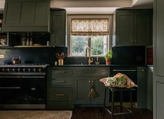 a kitchen with green cabinets and black counter tops is pictured in this image, there are flowers on the stool