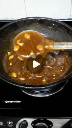 the food is being cooked in the pot on the stove top with a ladle