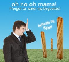 a man in a suit and tie holding his hand up to the sky while standing next to two large baguettes