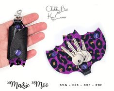 a hand holding a purple and black animal print keychain