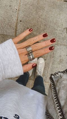 a woman's hand with two rings on her fingers, sitting next to a purse