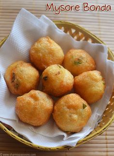 small fried food items in a basket on a wooden table with the words mysore bonda written above it