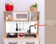 a toy kitchen with sink, stove and microwave on it's shelf next to the wall