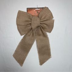 a brown bow on top of a piece of cloth next to a white wall with an orange tag