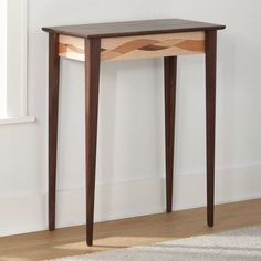 a small wooden table sitting on top of a hard wood floor next to a window