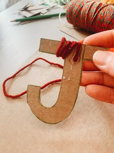 someone is making a wooden letter with yarn