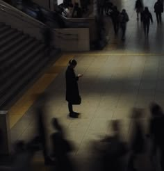 a man standing in the middle of a train station while looking at his cell phone