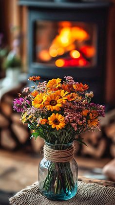 a vase filled with flowers sitting on top of a table next to a fire place