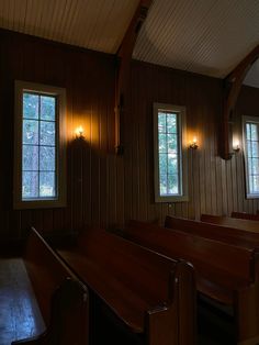 an empty church with wooden pews and three windows