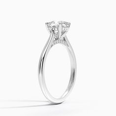 a white gold engagement ring with three stones on the band and an oval shaped center stone