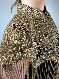 Shaak cape is a masterpiece with its shimmering gold beads and intricate embroidery throughout. The gold beaded fringe adds an extra layer of sophistication to this already exquisite piece. The golden beads used in the design are of the highest quality and glimmer with every movement of the wearer. The embroidery is beautifully crafted and adds texture and depth to the cape. The attention to detail is evident in every inch of this cape, making it a true work of art. Features: Beaded Tassel Hem C Festive Party Shawl With Sequins, Festive Sequin Shawl, Gold Bohemian Shawl For Wedding, Bohemian Gold Wedding Shawl, Gold Bohemian Wedding Shawl, Traditional Gold Pashmina Shawl, Gold Shawl For Festive Evening, Gold Shawl For Festive Evening Events, Gold Shawl For Evening And Festive Occasions