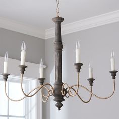 a chandelier with six candles hanging from it's arms in a room