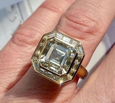 a close up of a person's hand with an engagement ring on their finger