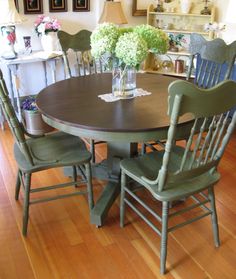 a dining room table with four chairs and flowers in a vase on the centerpiece