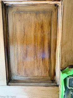 a close up of a wooden door with a green bag on the ground next to it