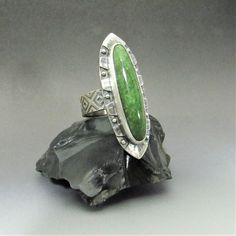 "Unique, eye catching nephrite jade ring is a one of a kind design in Argentium sterling silver and traditional sterling silver. A beautiful long slim jade cabochon is the star of this Aztec Mesoamerican inspired design. Jade was an integral component of Mesoamerican design and adornment, which is why as soon as I saw the stone there was a feeling of something from pre-Columbian times.  As the design coalesced in mind and matter, I soon realized the resemblance to the Azetc obsidian sword or Mac Nephrite Jade, Jade Ring, Art To Wear, Inspired Jewelry, Jewelry Maker, Sterling Silver Bands, Fine Silver, Silver Band, Rings Statement