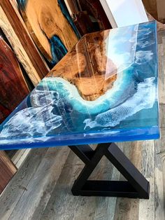 a glass table sitting on top of a wooden floor next to a wall with paintings behind it