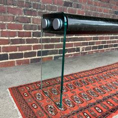 a large black object sitting on top of a red rug next to a brick wall