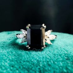 a black stone surrounded by crystal stones on top of a green cloth with silver accents