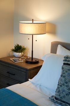 a bedroom with a bed, night stand and lamp on the bedside table in front of it