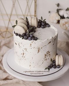 a white cake topped with blueberries and macaroons