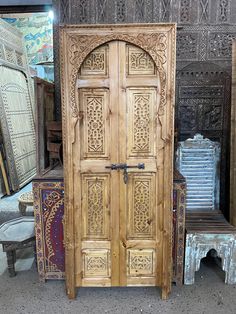 an old wooden door with intricate carvings on the front and sides, surrounded by other antique furniture