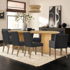 a dining room table with chairs and a vase on the rug in front of it