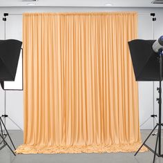 an empty photo studio with two light stands and three photography equipment in front of a yellow curtain