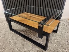 a glass and wood coffee table sitting on top of a carpeted floor next to a wall