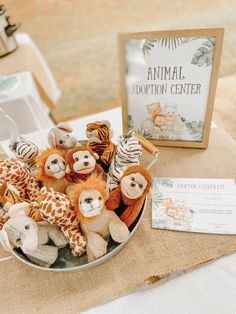 there are many stuffed animals in a bowl on the table next to a sign that says animal adoption center