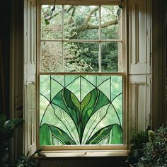 a stained glass window with green leaves in the center and below it is a potted plant