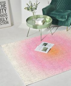 a living room with a green chair and pink rug on the floor next to a coffee table