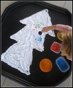 a child is painting on a tray with plastic cups