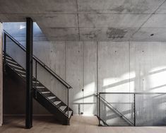 an empty room with stairs and railings in the center, surrounded by concrete walls