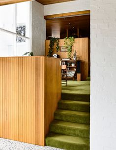 a room with green carpet and wooden stairs