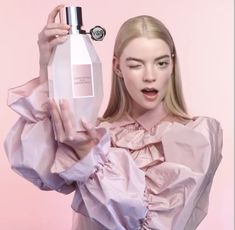 a woman holding a bottle of perfume in front of her face