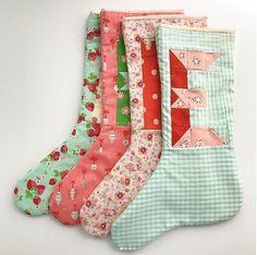 four christmas stockings are lined up on a white surface with red, green and pink designs