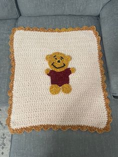 a crocheted winnie the pooh pillow on a couch