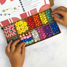 a child's hands holding a box of colorful beads and making them look like they are working on something