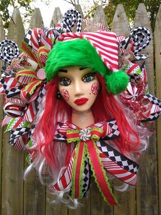 a close up of a doll with red hair and green eyes wearing a clown costume