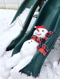 a snowman sitting on top of a slide with another snowman in the background