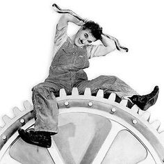 a man sitting on top of a giant gear wheel with a baseball bat in his hand