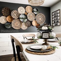 a dining room table set with plates and place settings on the wall above it is an arrangement of woven baskets