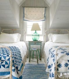 two beds in a room with white walls and blue rugs on the floor next to each other