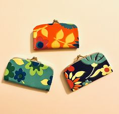 three purses sitting next to each other on top of a white surface with flowers