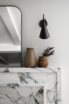 a marble fireplace mantel topped with vases and a mirror