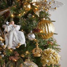 a christmas tree decorated with gold and silver ornaments, angel figurines and baubles